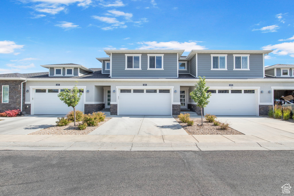 View of front of home with stone siding, concrete driveway, and a garage