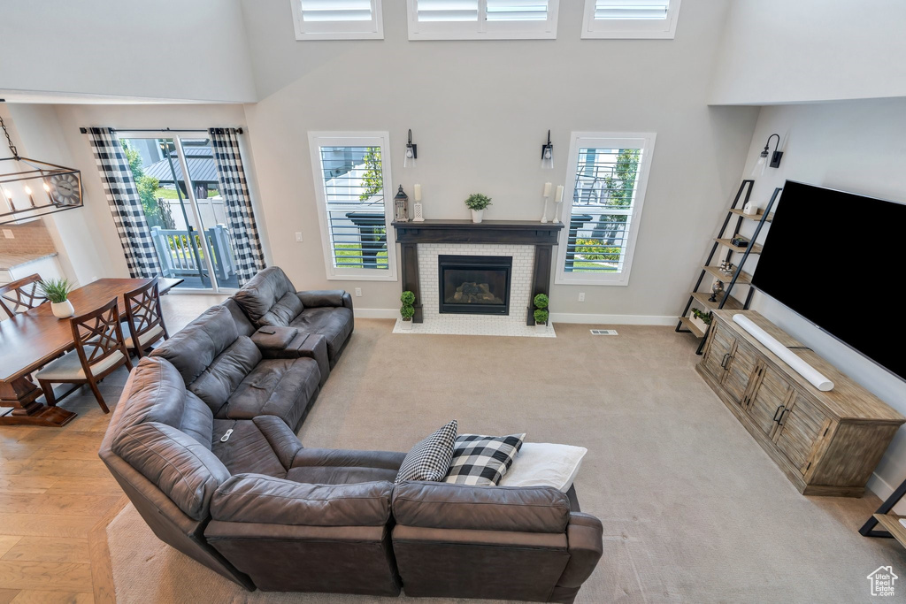 Living room featuring a towering ceiling, a fireplace with flush hearth, and healthy amount of natural light