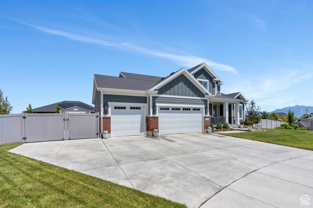 View of front of home featuring a gate, board and batten siding, an attached garage, and brick siding