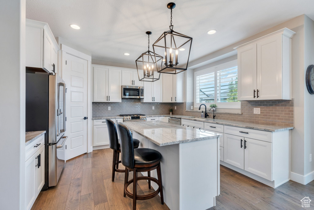 Kitchen with stainless steel appliances, white cabinets, a kitchen island, a chandelier, and recessed lighting