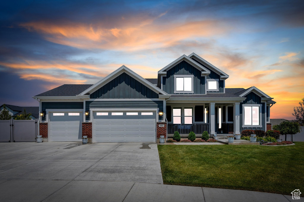 Craftsman-style home featuring covered porch, a garage, board and batten siding, driveway, and a gate