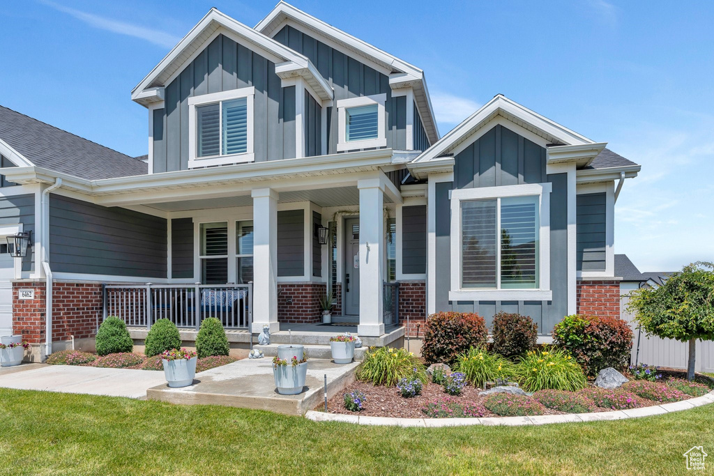 View of front of home featuring board and batten siding, a porch, and brick siding
