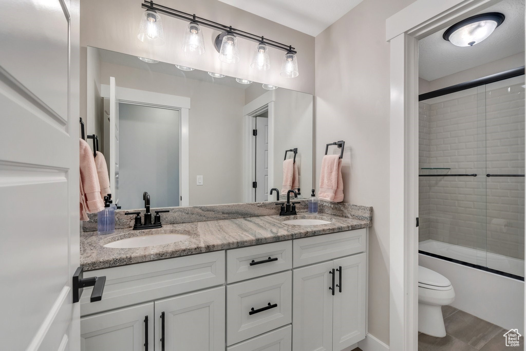 Bathroom featuring double vanity and shower / bath combination with glass door