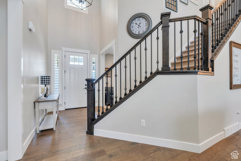 Entryway with a high ceiling, stairway, and wood finished floors