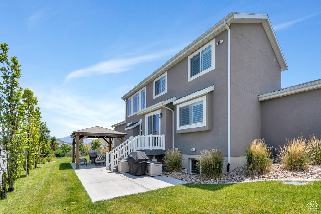Rear view of house with a gazebo, a patio area, stucco siding, and a yard