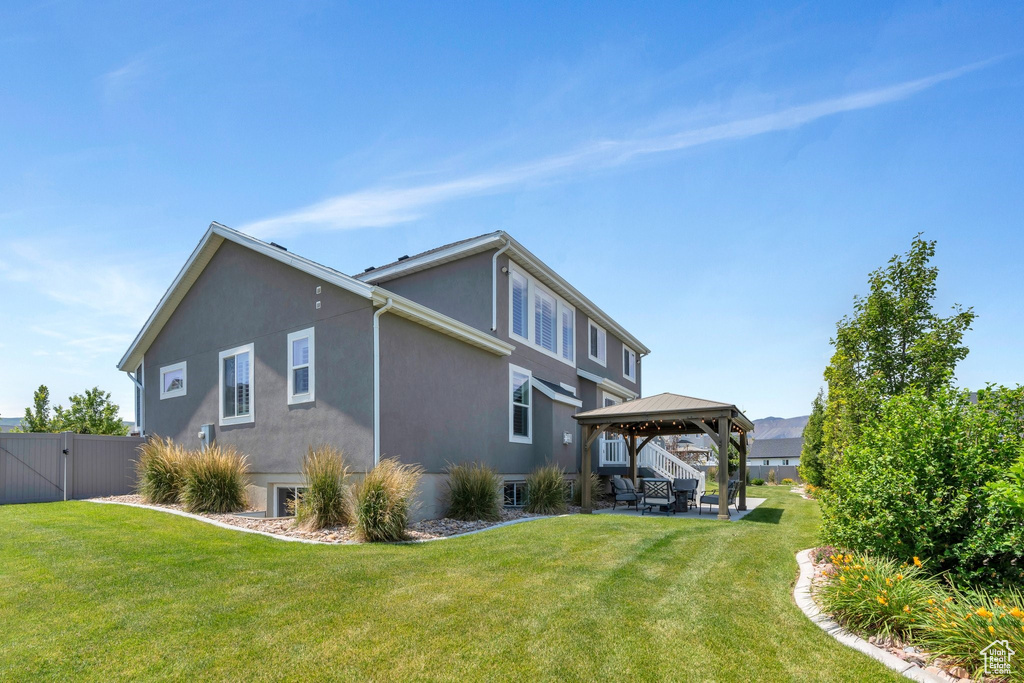 Rear view of house featuring a gazebo, stucco siding, a gate, and a patio area