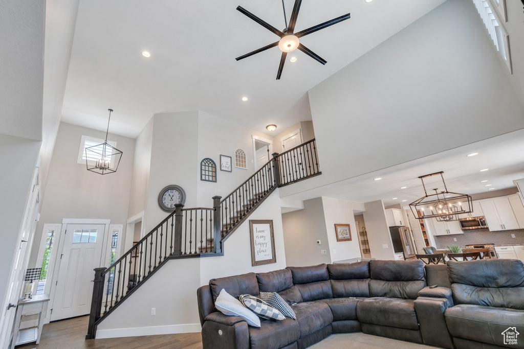 Living room with a high ceiling, a chandelier, stairs, recessed lighting, and a ceiling fan