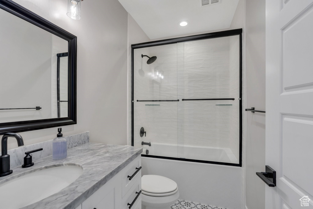 Bathroom featuring vanity, bath / shower combo with glass door, and recessed lighting