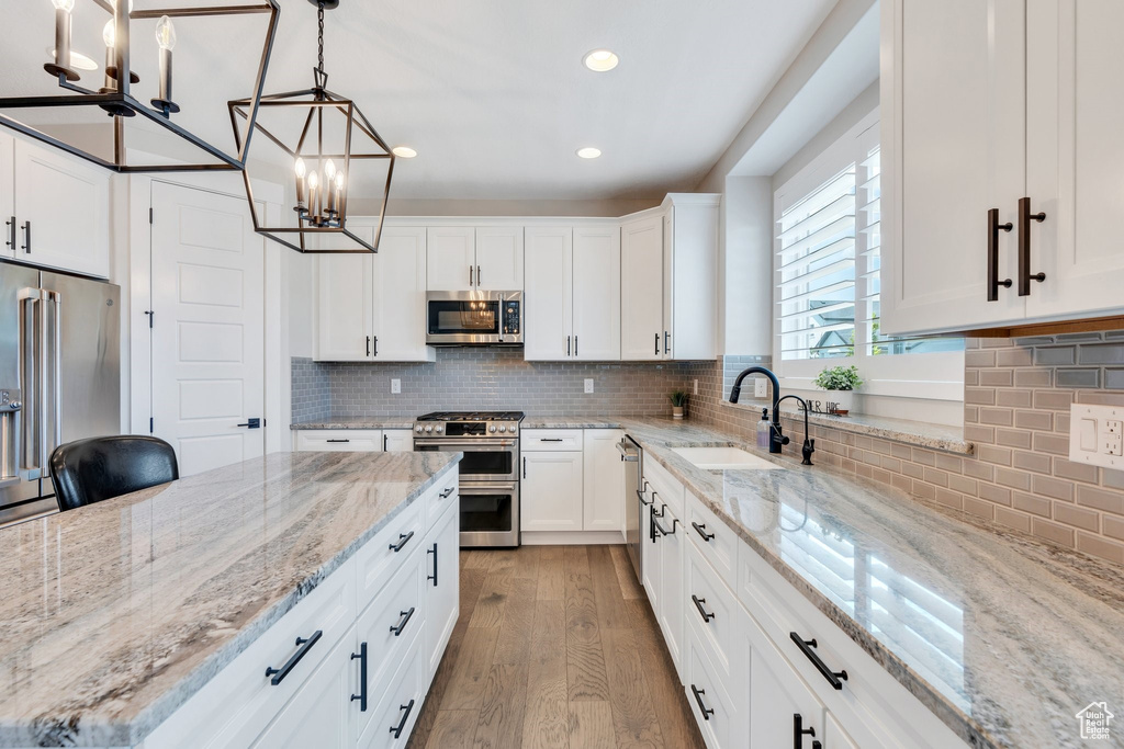 Kitchen featuring appliances with stainless steel finishes, a chandelier, recessed lighting, light wood finished floors, and decorative backsplash