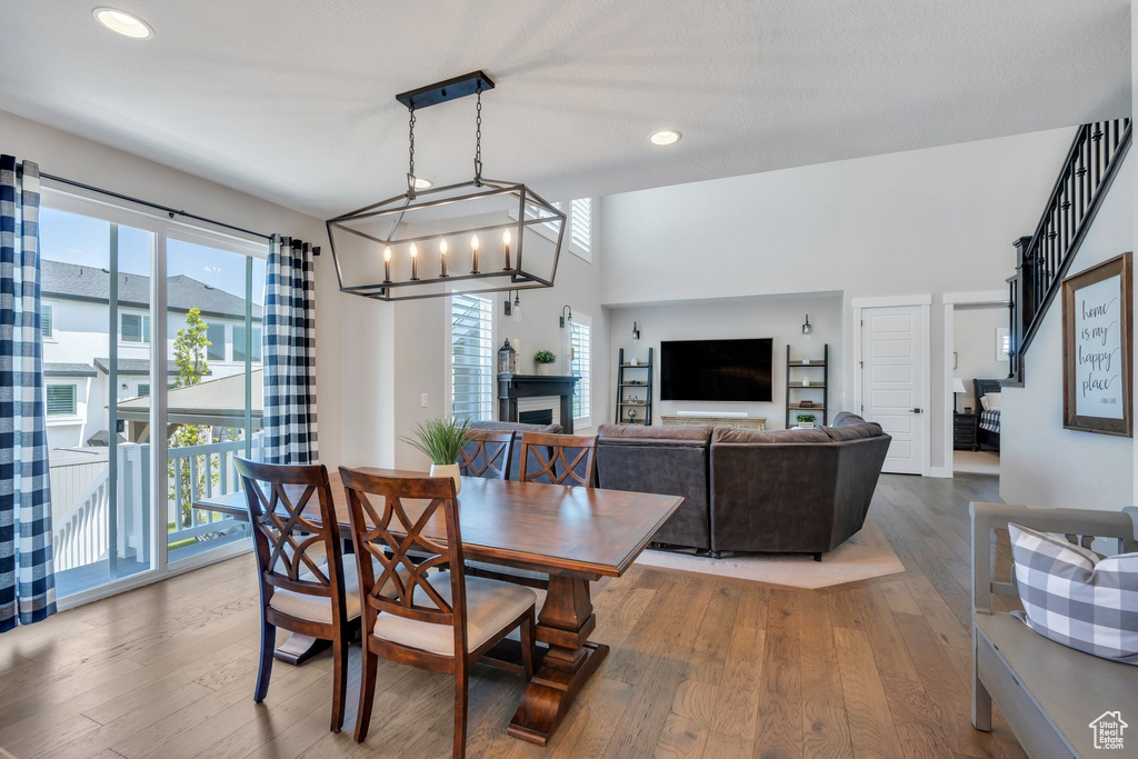 Dining room featuring healthy amount of natural light, wood finished floors, recessed lighting, a fireplace, and a chandelier