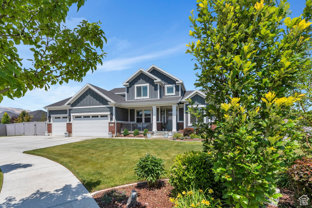 Craftsman inspired home featuring covered porch, board and batten siding, driveway, brick siding, and a garage