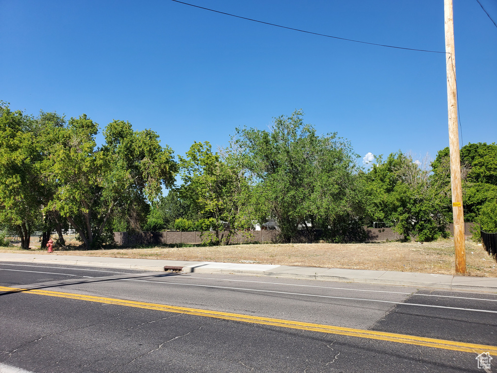 View of asphalt street featuring sidewalks and view of scattered trees