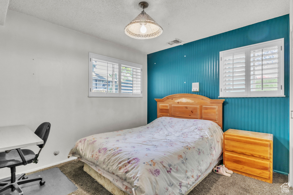 Carpeted bedroom featuring a textured ceiling and a desk