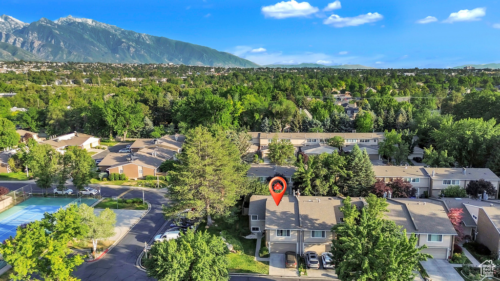 Aerial perspective of suburban area with a mountainous background and a heavily wooded area
