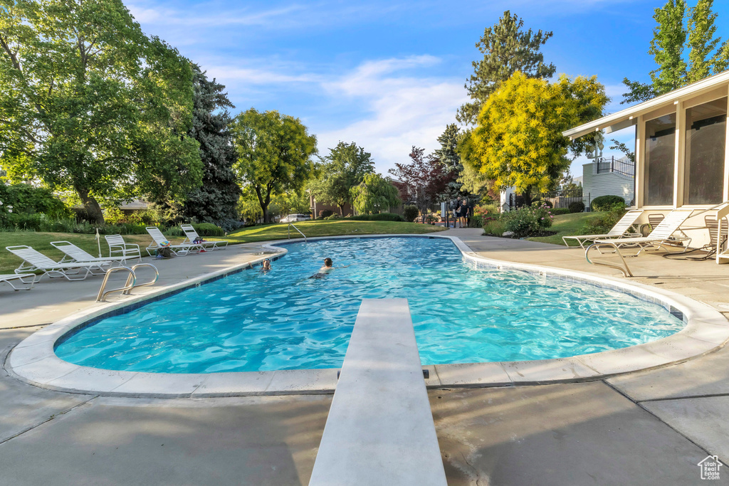 Swimming pool featuring a patio area, a diving board, and a yard