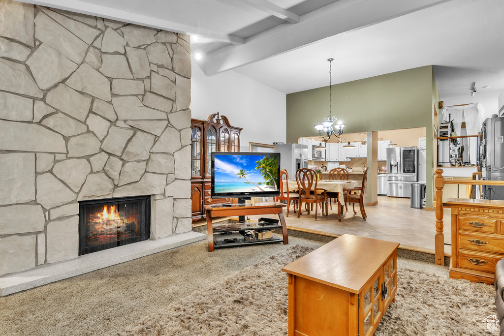 Living area with a chandelier, beam ceiling, and a stone fireplace