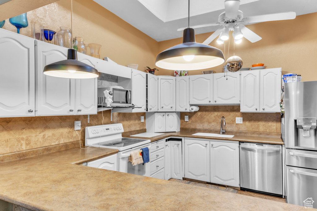Kitchen with appliances with stainless steel finishes, backsplash, ceiling fan, and white cabinetry