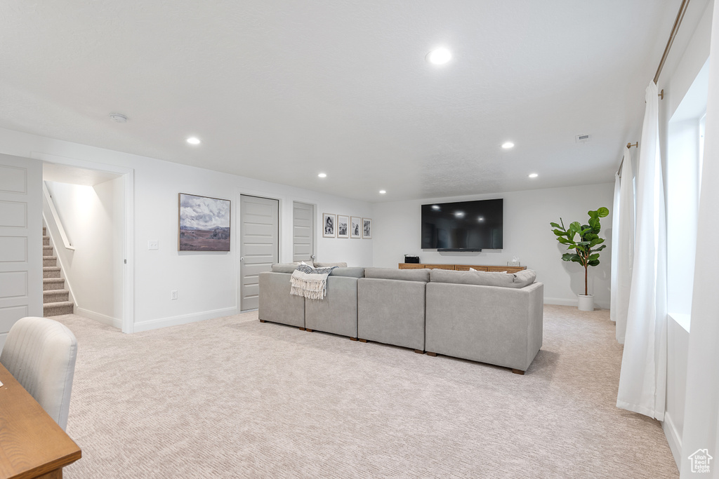 Living area featuring light colored carpet, stairway, and recessed lighting