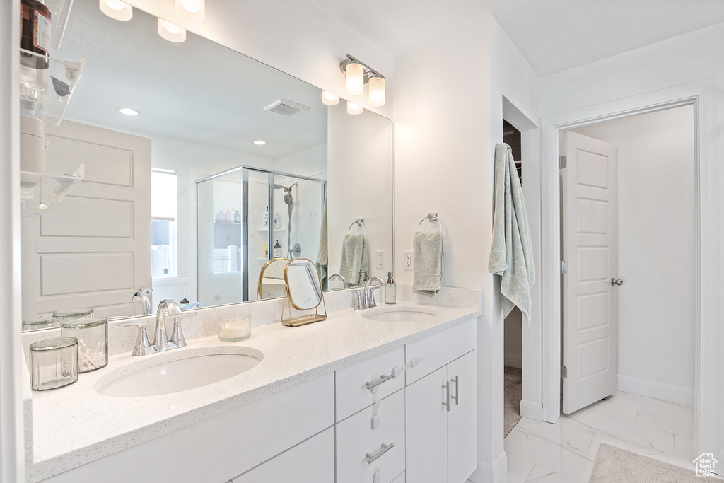 Full bath featuring a stall shower, double vanity, marble finish flooring, and recessed lighting