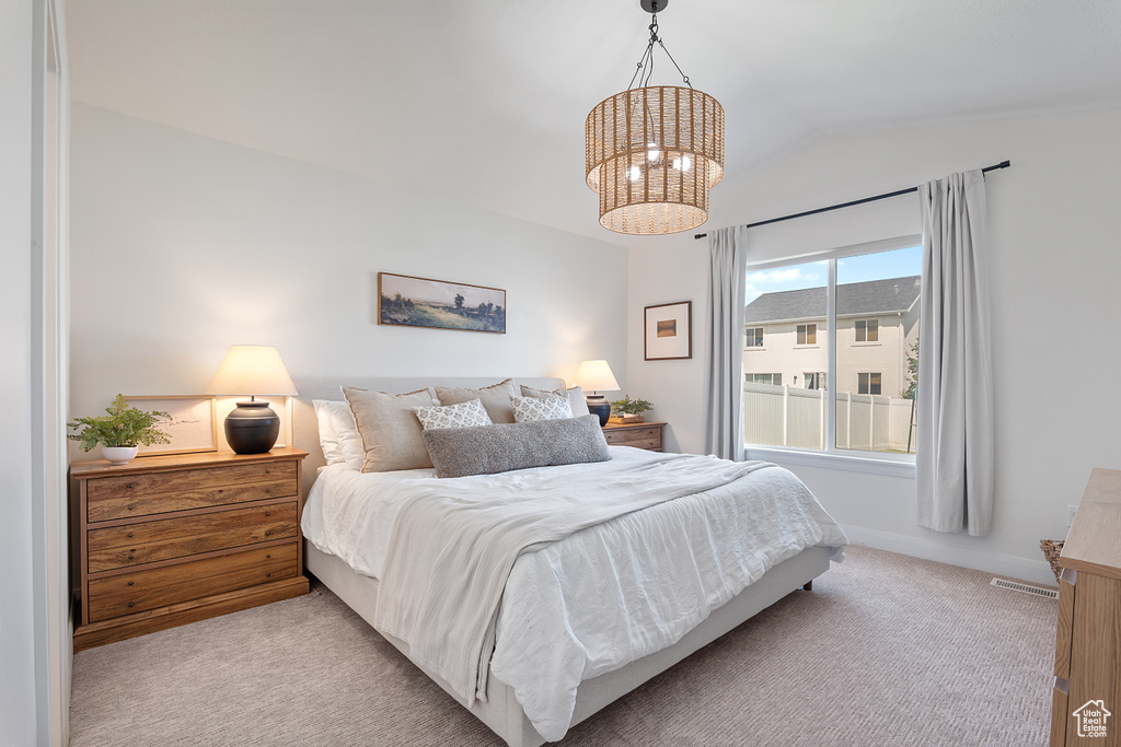 Carpeted bedroom with lofted ceiling and a chandelier