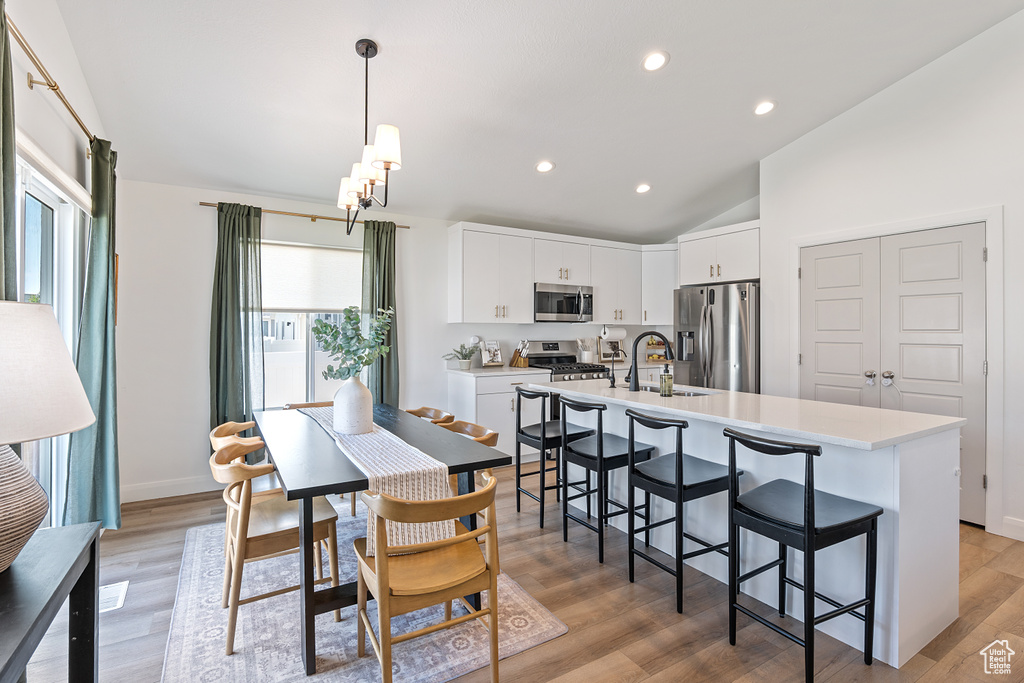 Dining area featuring vaulted ceiling, recessed lighting, light wood-style floors, and a chandelier