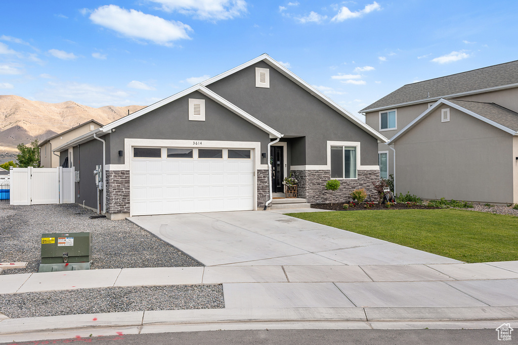 View of front of property with stone siding, stucco siding, and a garage