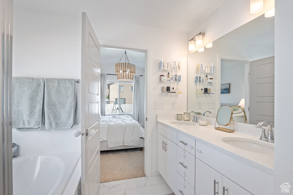 Bathroom featuring double vanity, ensuite bath, a garden tub, a chandelier, and marble look tile flooring