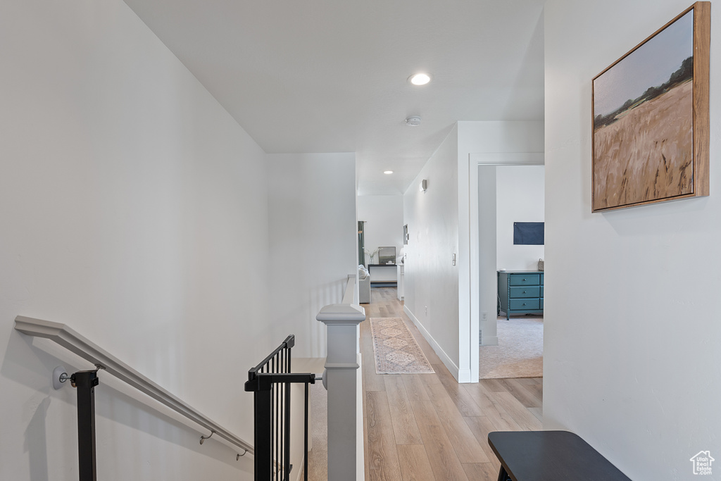 Hall with an upstairs landing, light wood finished floors, and recessed lighting