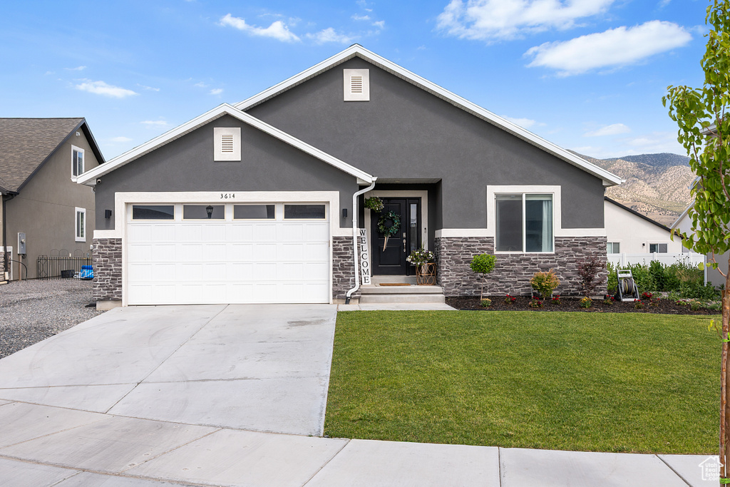 View of front of property with stone siding, stucco siding, and a front yard