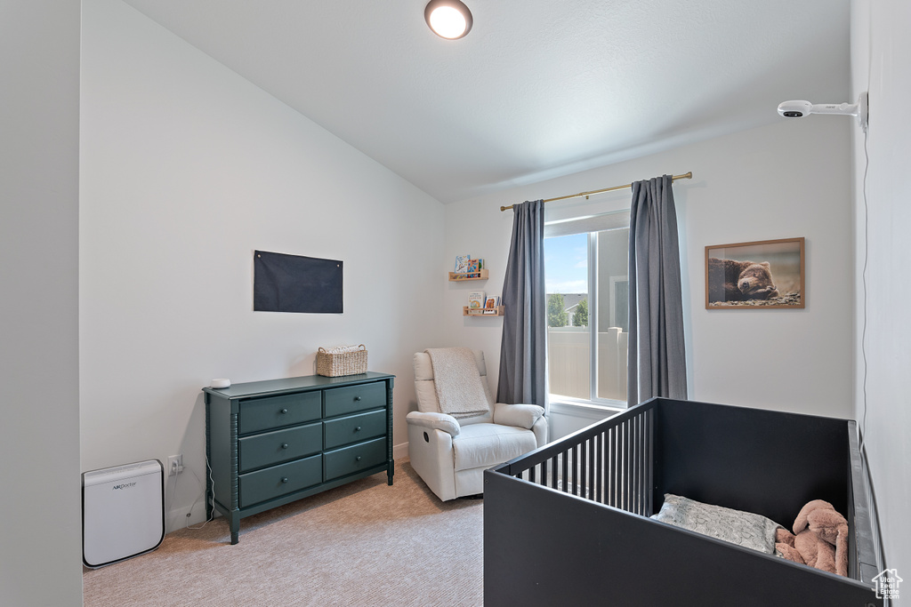 Bedroom with lofted ceiling, carpet floors, and a crib