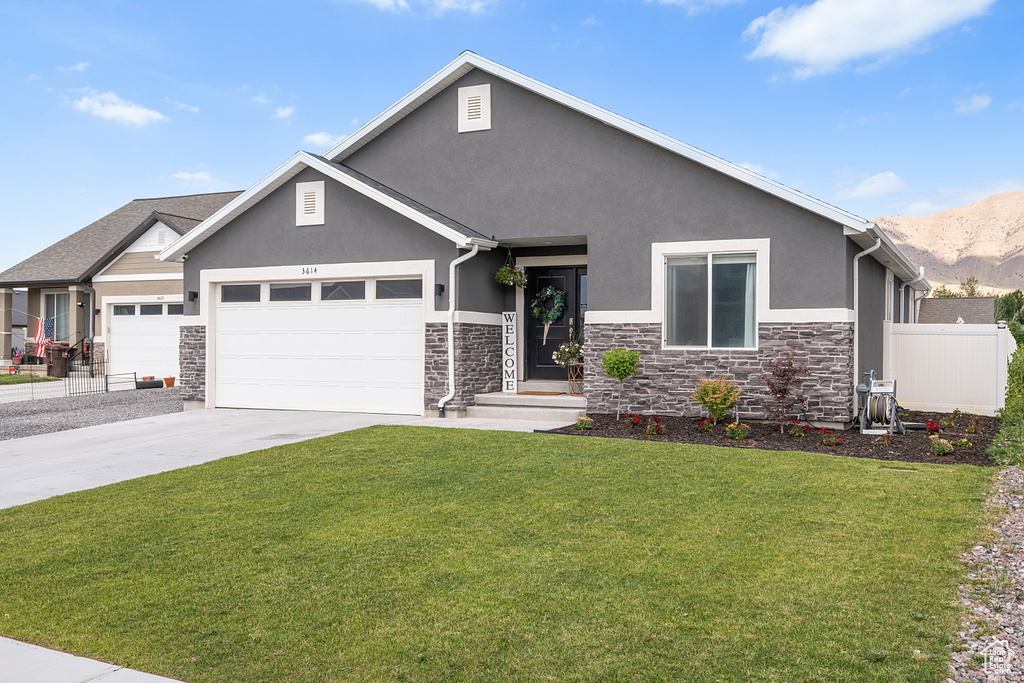 View of front facade with stone siding, stucco siding, a garage, concrete driveway, and a mountain view