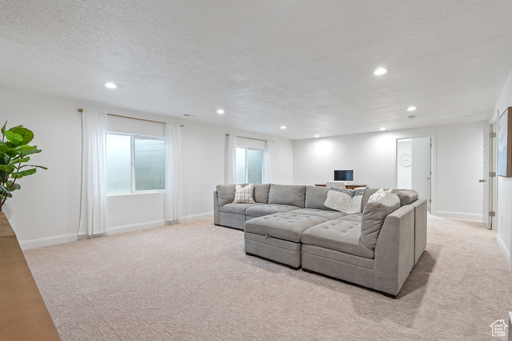 Carpeted living area with recessed lighting and a textured ceiling