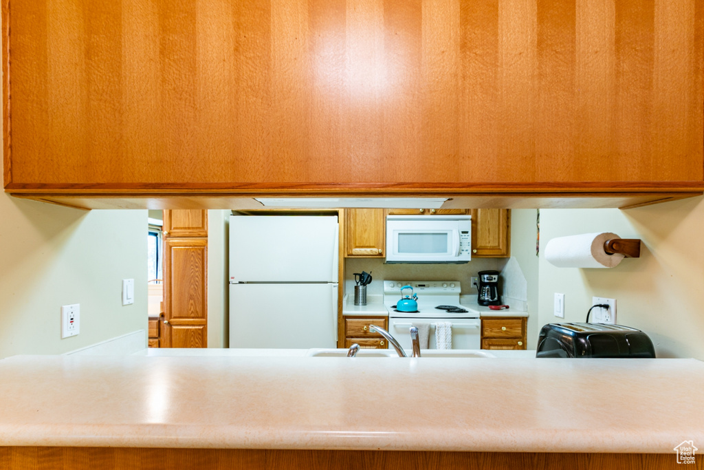 Kitchen featuring white appliances, a peninsula, and light countertops