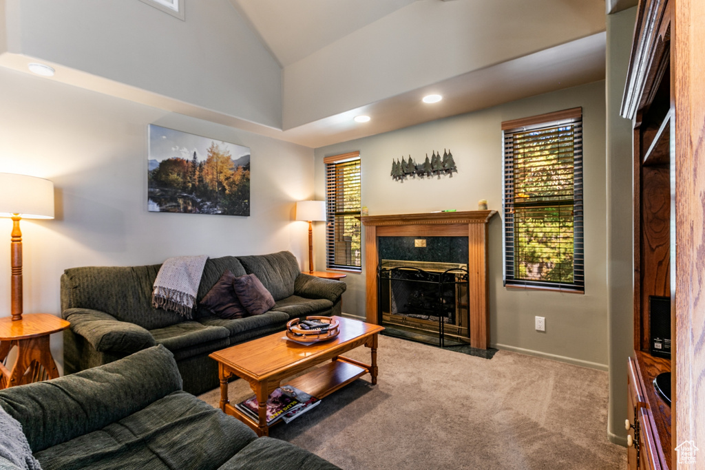 Carpeted living room with healthy amount of natural light, vaulted ceiling, recessed lighting, and a premium fireplace