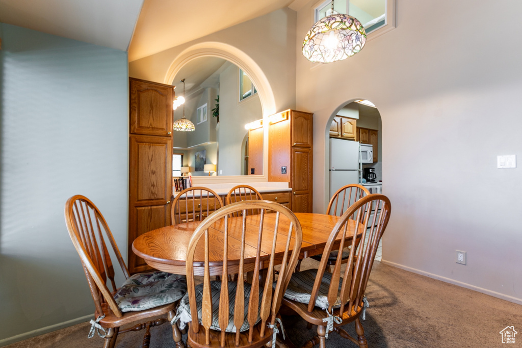 Carpeted dining room featuring arched walkways and high vaulted ceiling