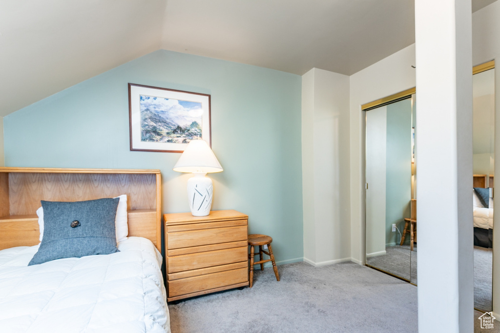 Carpeted bedroom featuring lofted ceiling and a closet