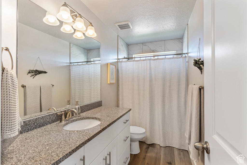 Full bath with vanity, wood finished floors, a shower with curtain, and a textured ceiling