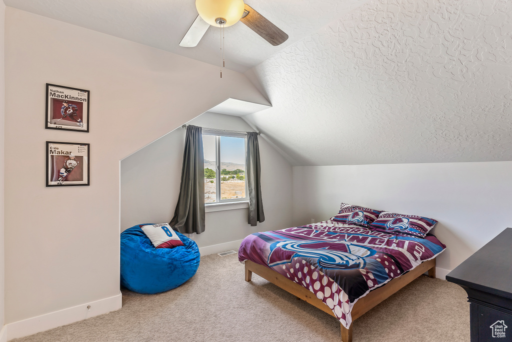Bedroom featuring carpet, lofted ceiling, ceiling fan, and a textured ceiling