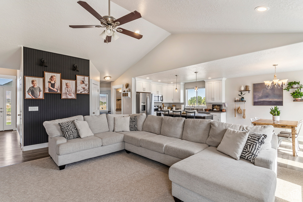 Living area with a chandelier, a ceiling fan, recessed lighting, wood finished floors, and high vaulted ceiling