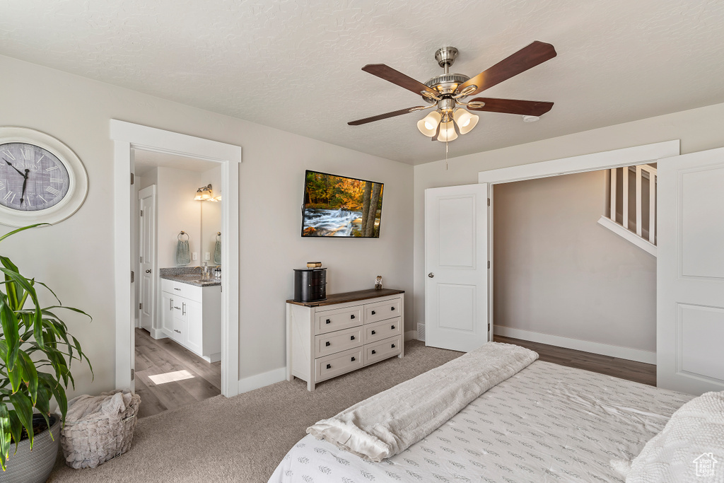 Carpeted bedroom with a ceiling fan, wood finished floors, and connected bathroom