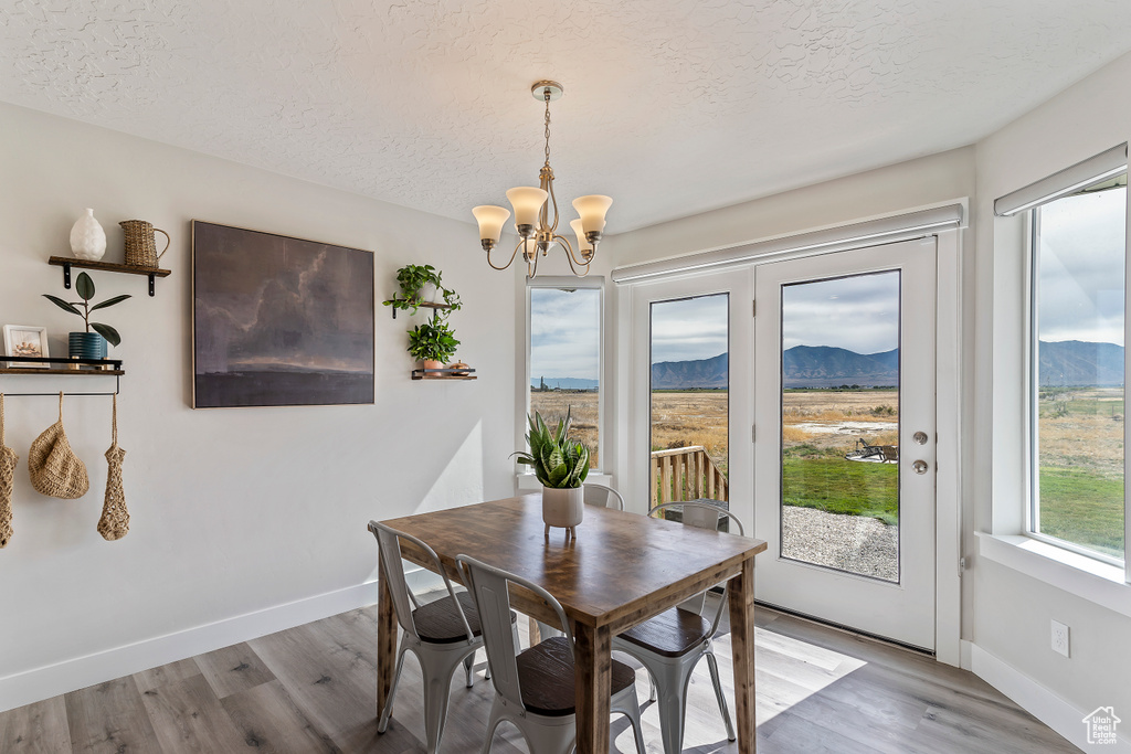 Dining room featuring a mountain view, a textured ceiling, a chandelier, and wood finished floors