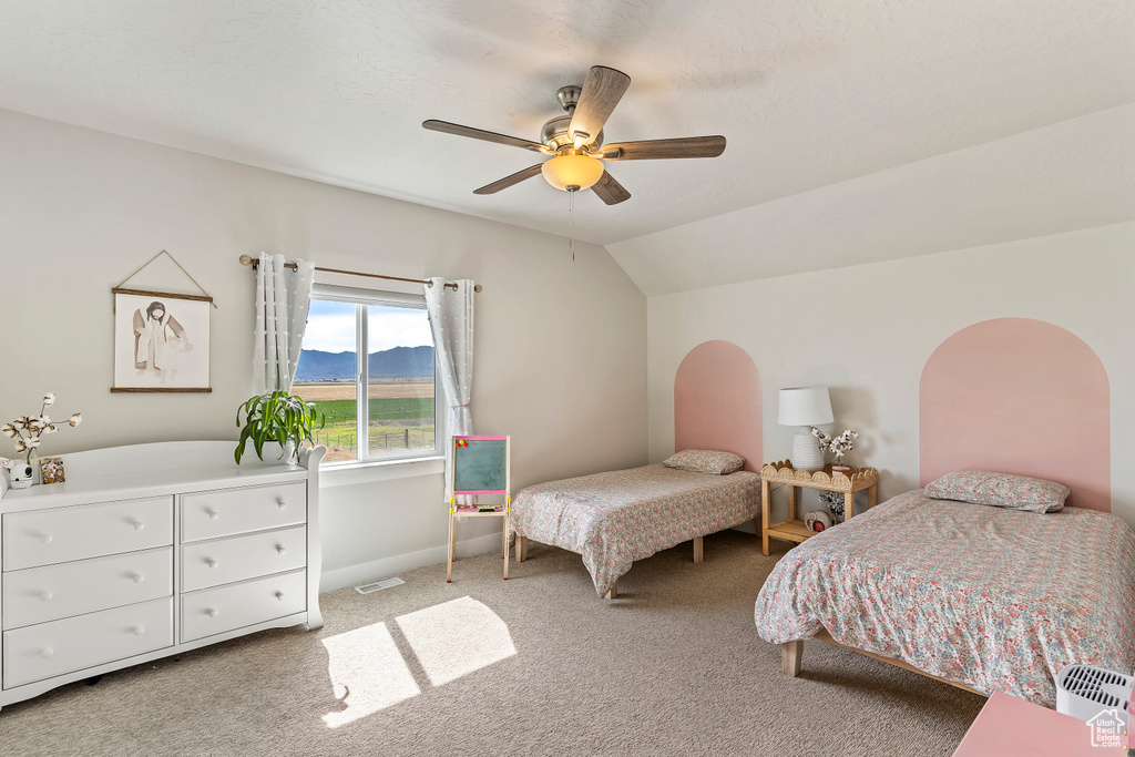 Bedroom featuring light carpet, lofted ceiling, and a ceiling fan
