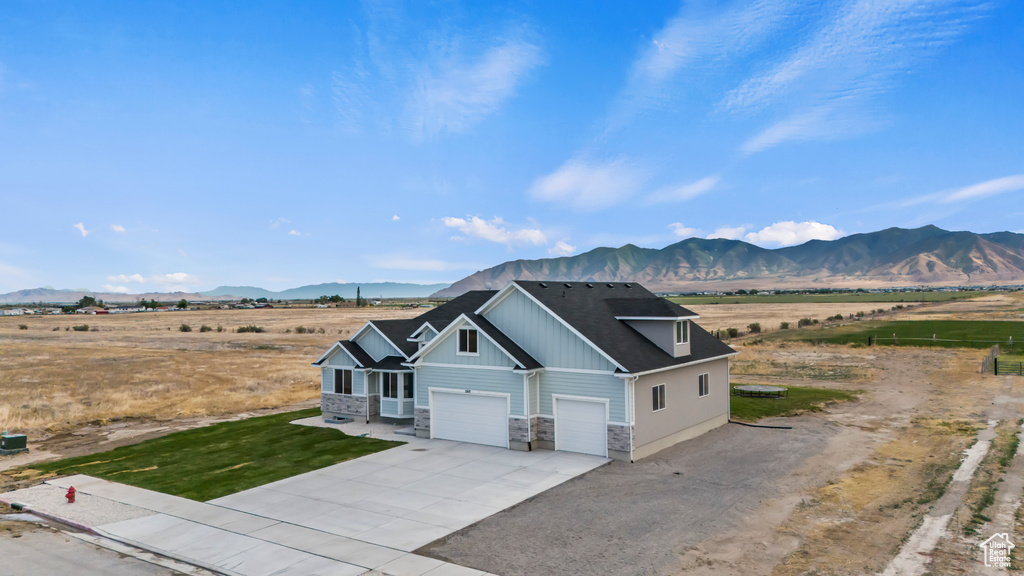 View of front of house featuring stone siding, a mountain view, driveway, and board and batten siding