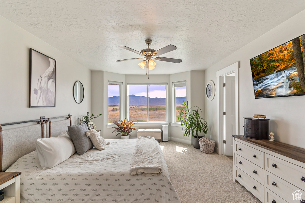 Bedroom with light carpet, a textured ceiling, and a ceiling fan