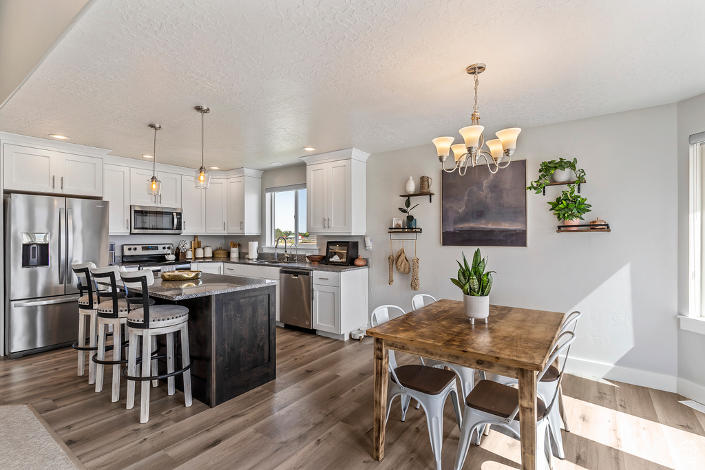 Kitchen with stainless steel appliances, dark wood finished floors, recessed lighting, a chandelier, and white cabinets