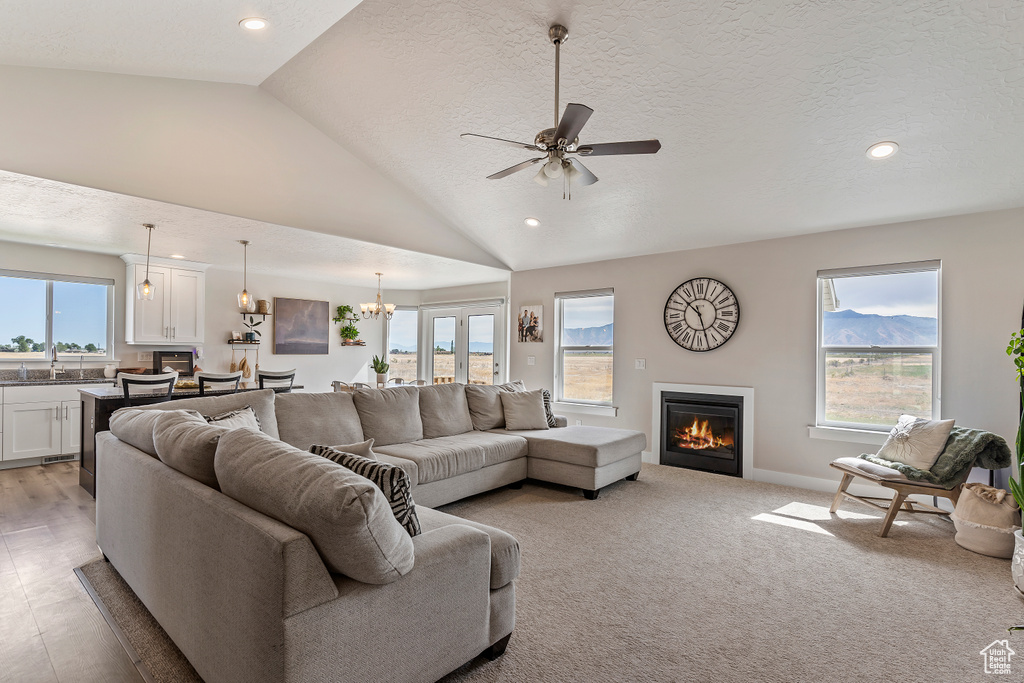 Living room with a glass covered fireplace, recessed lighting, vaulted ceiling, a ceiling fan, and a chandelier
