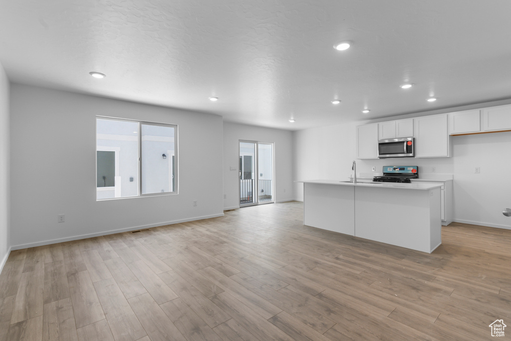 Kitchen featuring stainless steel appliances, white cabinetry, light wood-style floors, light countertops, and recessed lighting