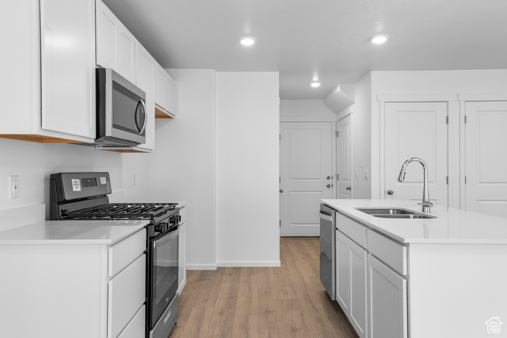 Kitchen featuring stainless steel appliances, light wood-type flooring, light countertops, white cabinetry, and recessed lighting