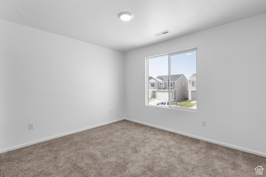 Carpeted spare room featuring baseboards