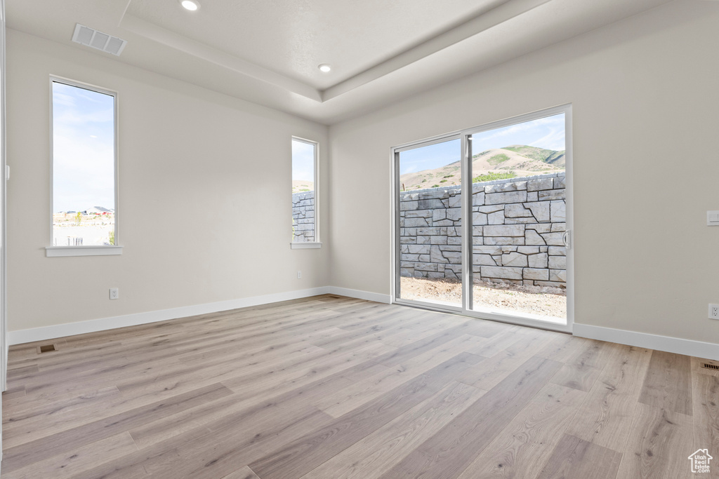 Spare room with light wood-style floors, a tray ceiling, and recessed lighting